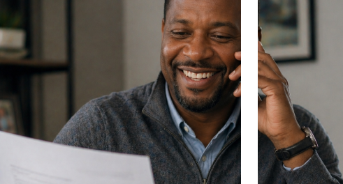 Man smiling while reviewing documents and speaking on the phone in an office