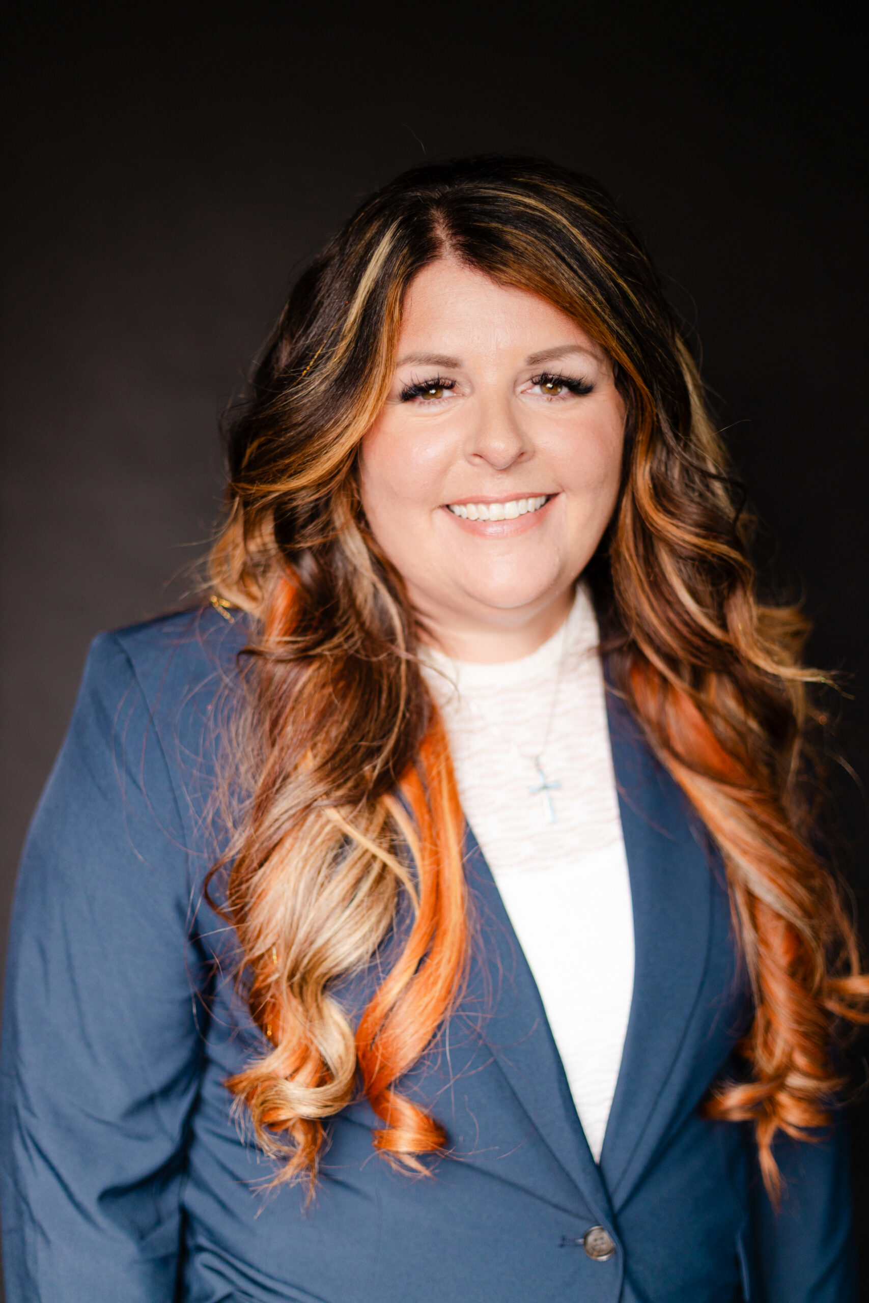 Professional portrait of a female legal professional wearing a navy blazer and white blouse against a dark studio background.