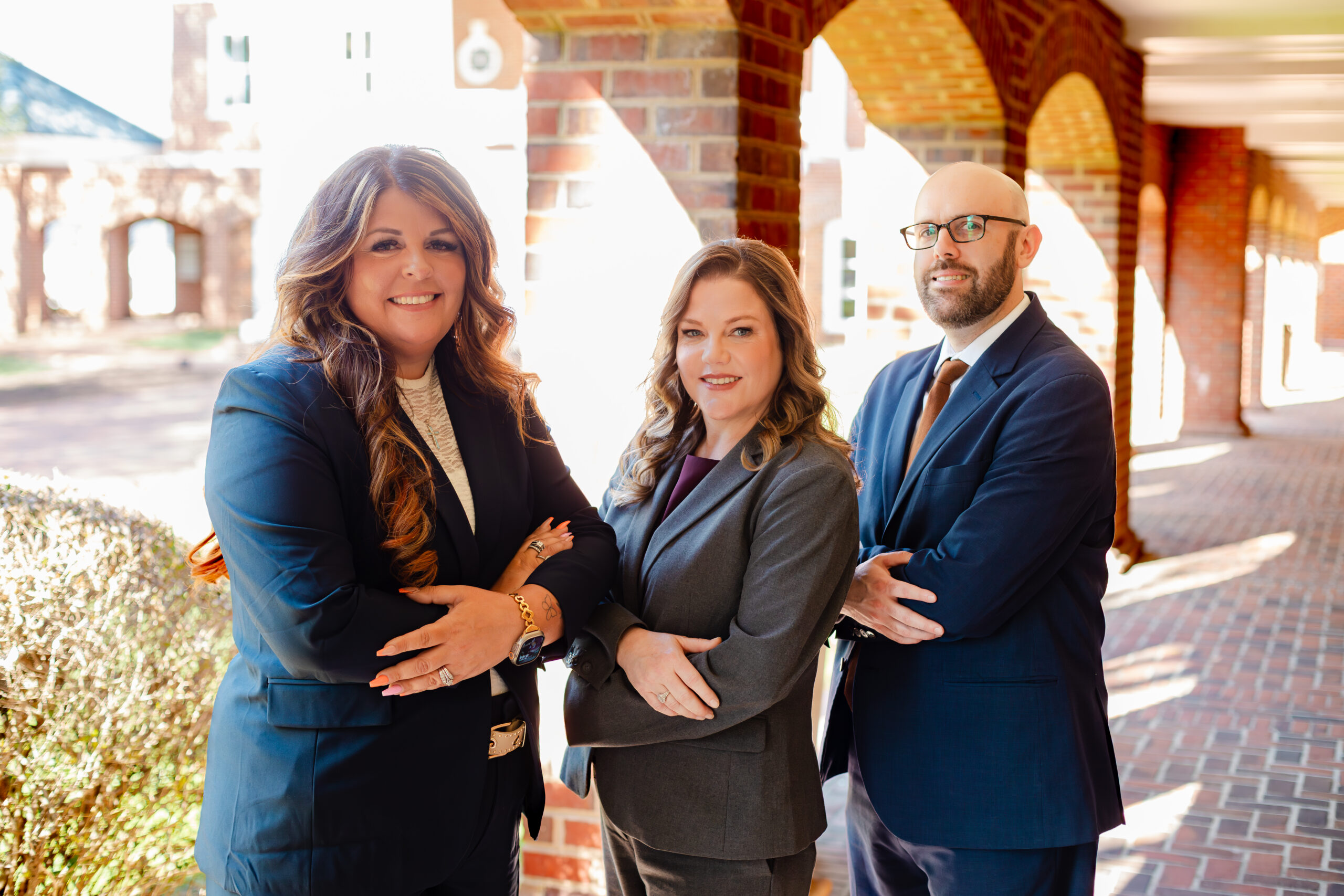 Three attorneys standing together outside a law office in professional business attire.